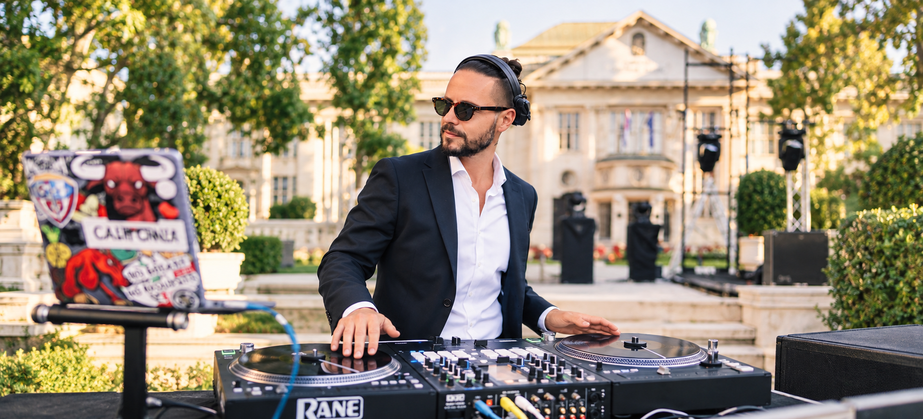 Luca Goya mixing on turntables in a navy jacket at an outdoor celebration