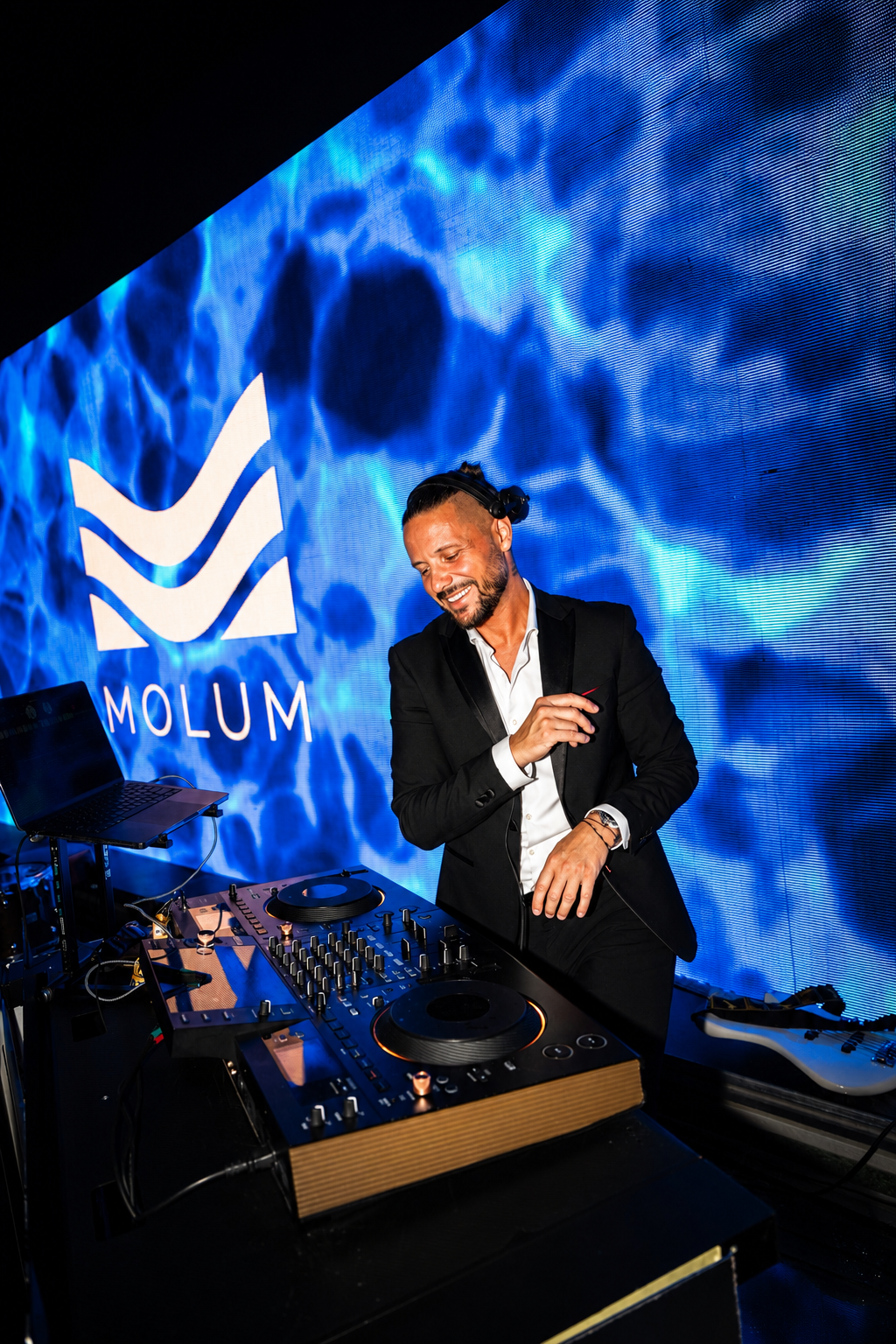 Luca performing in a dark suit against blue event lighting